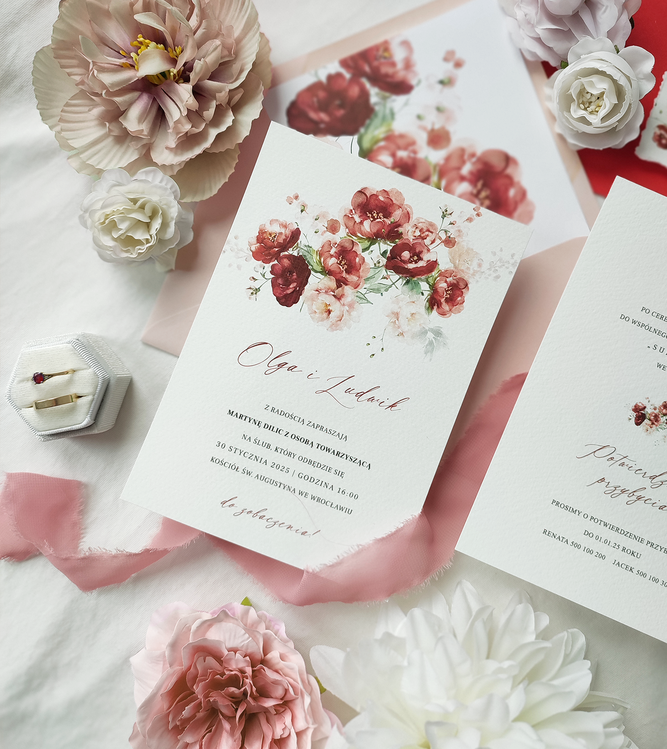 Eleganckie personalizowane zaproszenia ślubne, którego motywem są czerwone kwiaty, przeplatane zielonymi listkami. Różowa wstążka szyfonowa oraz różowa koperta B6 dopełniają zaproszenia na ślub i sprawiają, że są bardzo eleganckie, kolorowe i radosne.