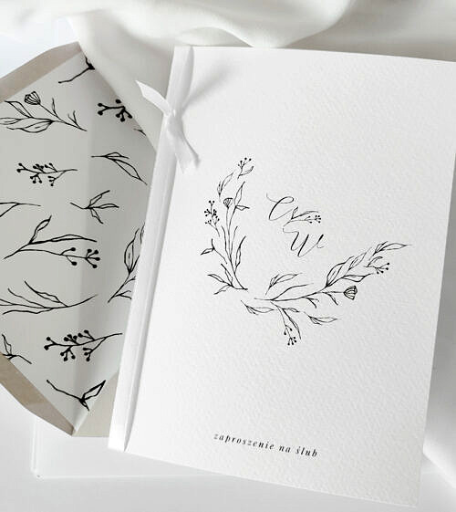 Nowoczesne, minimalistyczne zaproszenia ślubne z białą wstążką. Z wiankiem w ręcznie rysowanym wiankiem w listki oraz kaligrafia.