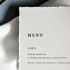 Proste, leżące na talerzu menu weselne wykonane na papierze imitujący papier czerpany.