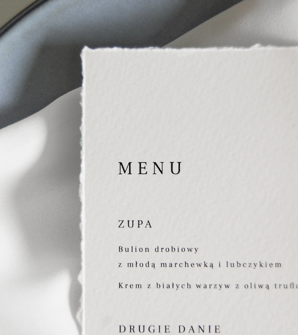 Proste, leżące na talerzu menu weselne wykonane na papierze imitujący papier czerpany.